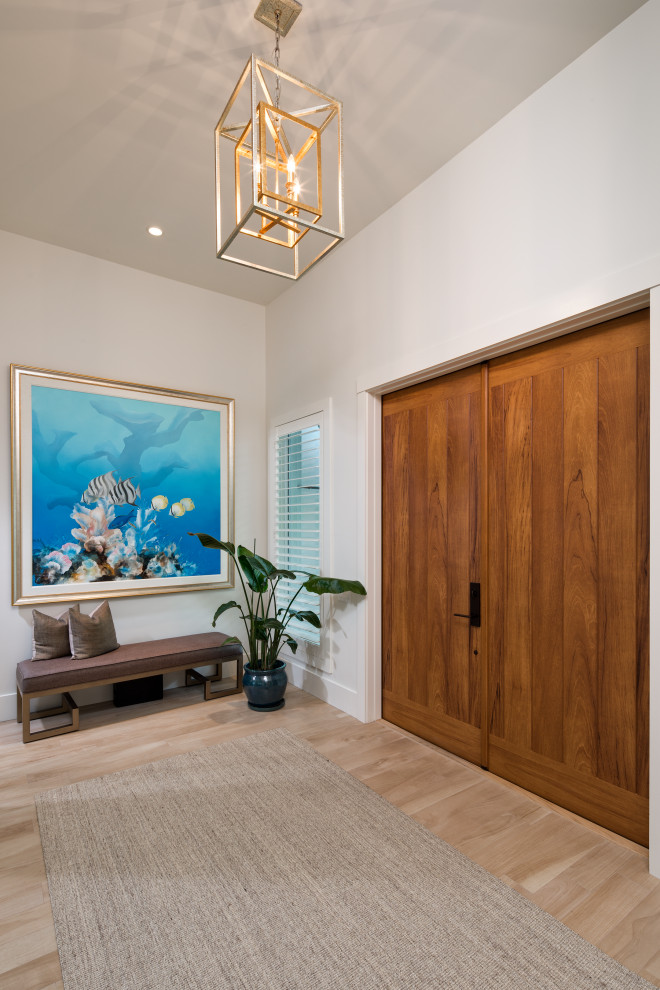 Inspiration for a mid-sized tropical front door in Other with white walls, light hardwood floors, a double front door, a medium wood front door and brown floor.