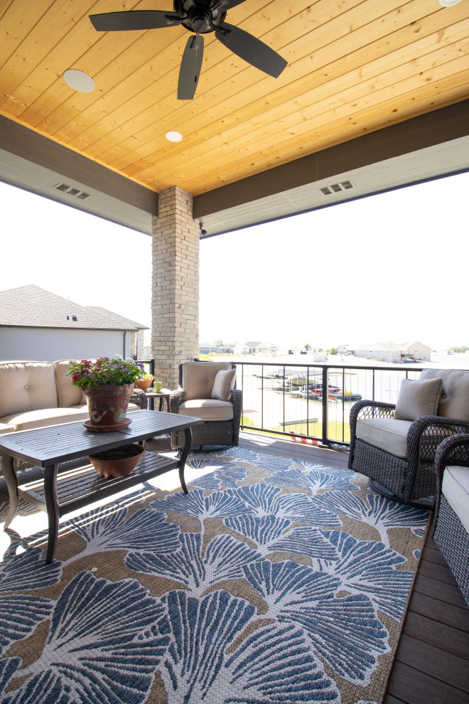 This is an example of a modern backyard and first floor deck in Omaha with a roof extension and cable railing.