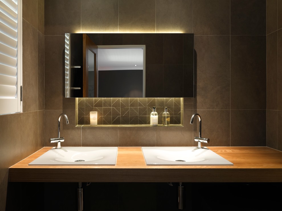 Photo of a contemporary bathroom in Sydney with flat-panel cabinets, wood benchtops, brown tile, a drop-in sink and brown benchtops.