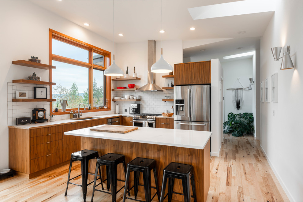 Inspiration for a mid-sized contemporary l-shaped kitchen in Other with flat-panel cabinets, medium wood cabinets, white splashback, subway tile splashback, stainless steel appliances, with island, white benchtop, an undermount sink, quartzite benchtops, medium hardwood floors and brown floor.
