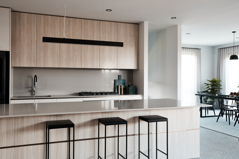 Inspiration for a mid-sized contemporary single-wall eat-in kitchen in Melbourne with an undermount sink, flat-panel cabinets, light wood cabinets, solid surface benchtops, beige splashback, glass sheet splashback, terrazzo floors, with island, grey floor and beige benchtop.