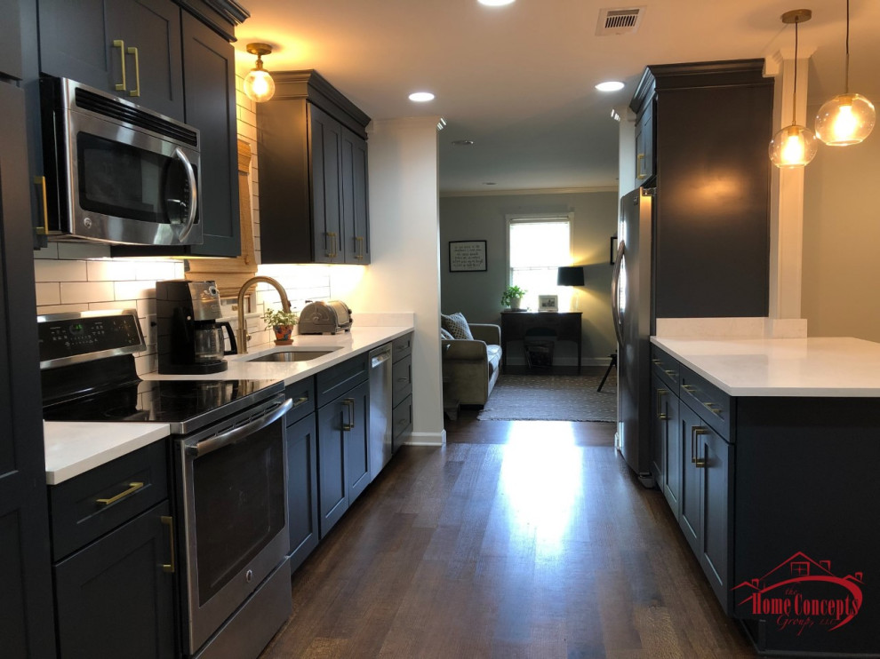Mid-sized transitional galley medium tone wood floor open concept kitchen photo with an undermount sink, shaker cabinets, blue cabinets, quartzite countertops, white backsplash, ceramic backsplash, stainless steel appliances, a peninsula and white countertops