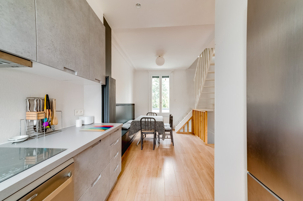Exemple de cuisine ouverte in U With sol en stratifié, un sol beige, un évier encastré, un placard à porte plane, des portes de placard grises, un plan de travail en stratifié, une crédence blanche, une crédence en carreau de porcelaine, un électroménager en acier inoxydable, aucun îlot and un plan de travail gris.