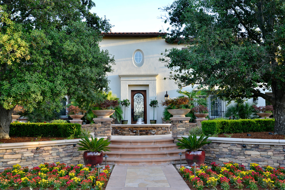 Large mediterranean front yard patio in San Diego with a water feature, natural stone pavers and a pergola.