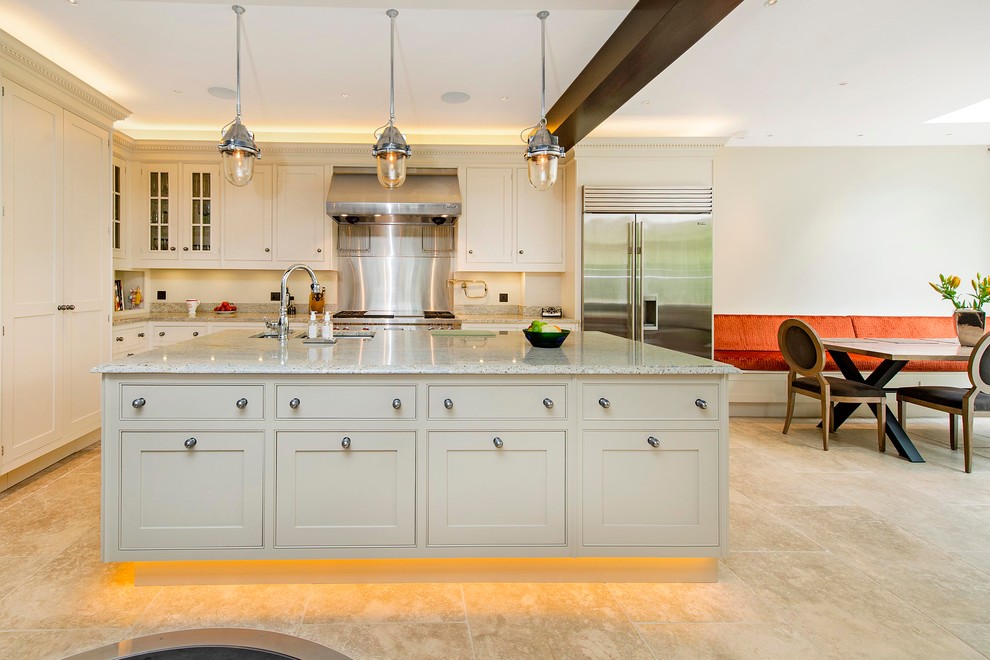 Photo of a contemporary l-shaped eat-in kitchen in London with an undermount sink, shaker cabinets, beige cabinets, metallic splashback, stainless steel appliances and with island.