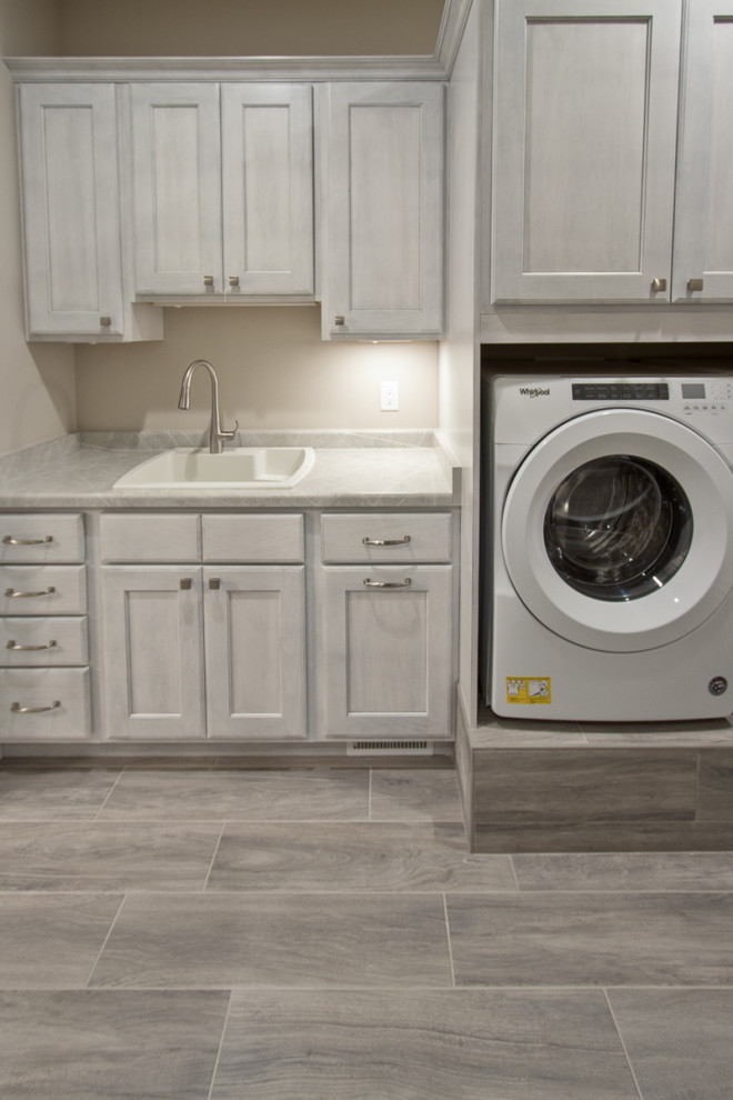 Design ideas for a transitional utility room in Other with recessed-panel cabinets, medium wood cabinets, laminate benchtops, beige walls, porcelain floors, a side-by-side washer and dryer, grey floor and white benchtop.