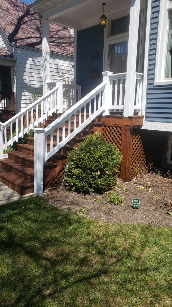 This is an example of a mid-sized cottage wood railing porch design in Chicago with an awning.