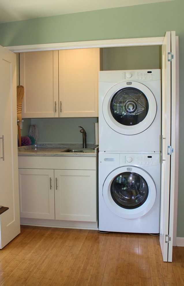 Design ideas for a large transitional galley laundry cupboard in Los Angeles with an undermount sink, shaker cabinets, white cabinets, quartzite benchtops, green walls, bamboo floors and a stacked washer and dryer.