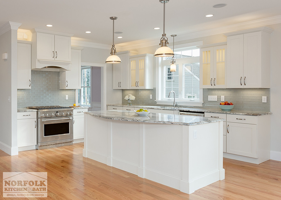 Large transitional l-shaped open plan kitchen in Boston with an undermount sink, shaker cabinets, white cabinets, granite benchtops, grey splashback, subway tile splashback, stainless steel appliances, light hardwood floors and with island.