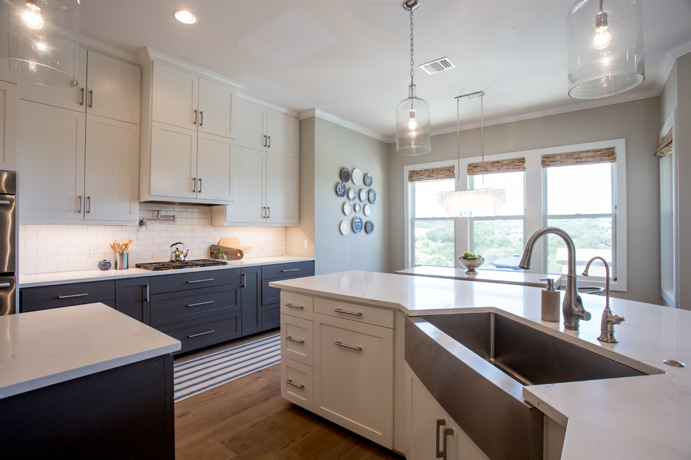 Example of a transitional light wood floor and beige floor eat-in kitchen design in Austin with a farmhouse sink, shaker cabinets, white cabinets, quartz countertops, white backsplash, subway tile backsplash, stainless steel appliances and an island