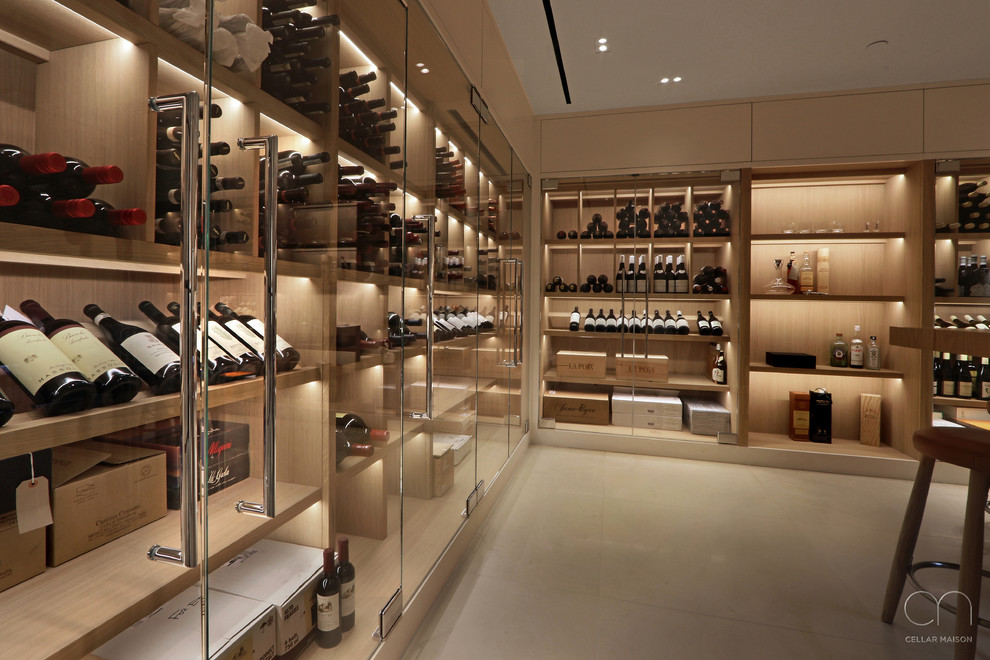 This is an example of a large contemporary wine cellar in London with limestone floors, display racks and white floor.