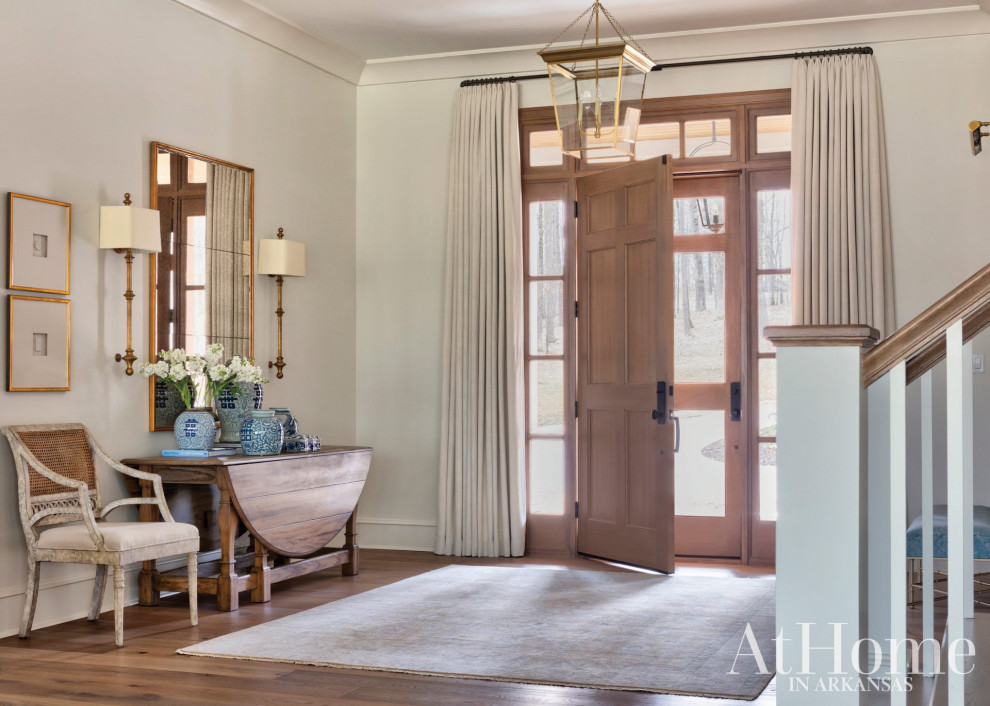 Inspiration for a large transitional light wood floor and brown floor entryway remodel in Little Rock with white walls and a light wood front door