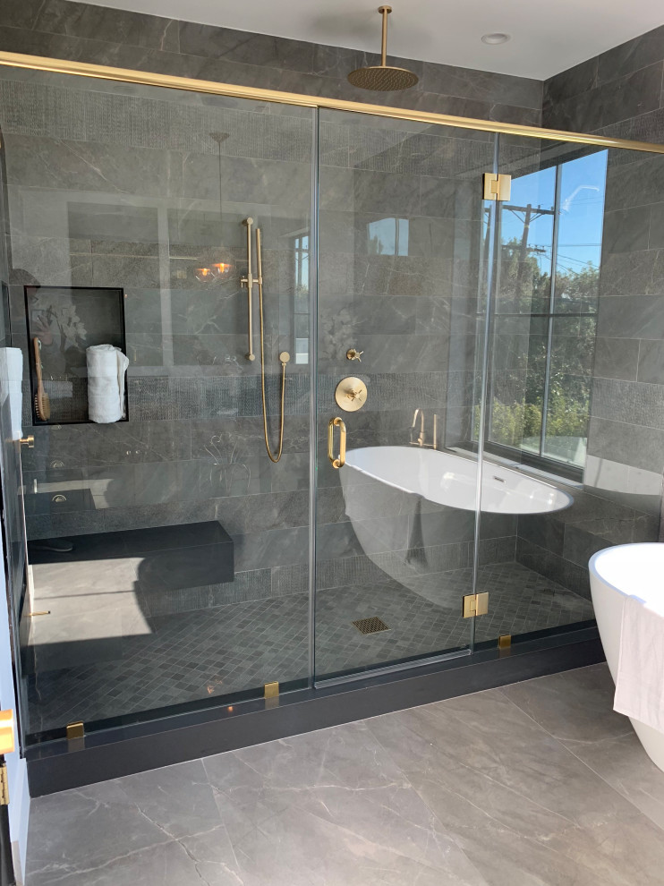 Large transitional master bathroom in Los Angeles with shaker cabinets, dark wood cabinets, a freestanding tub, an alcove shower, a two-piece toilet, gray tile, limestone, white walls, limestone floors, an undermount sink, engineered quartz benchtops, grey floor, a hinged shower door and grey benchtops.