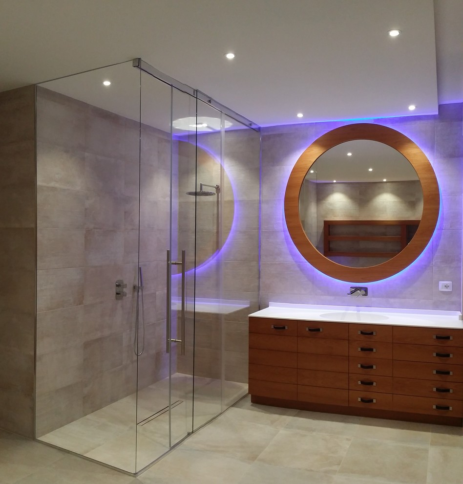 This is an example of a large contemporary master bathroom in Turin with flat-panel cabinets, medium wood cabinets, a freestanding tub, a curbless shower, a two-piece toilet, beige tile, porcelain tile, white walls, porcelain floors, an integrated sink and solid surface benchtops.