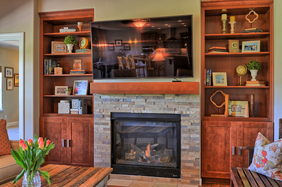This is an example of a mid-sized eclectic open concept family room in Other with beige walls, laminate floors, a standard fireplace, a stone fireplace surround, a wall-mounted tv and brown floor.