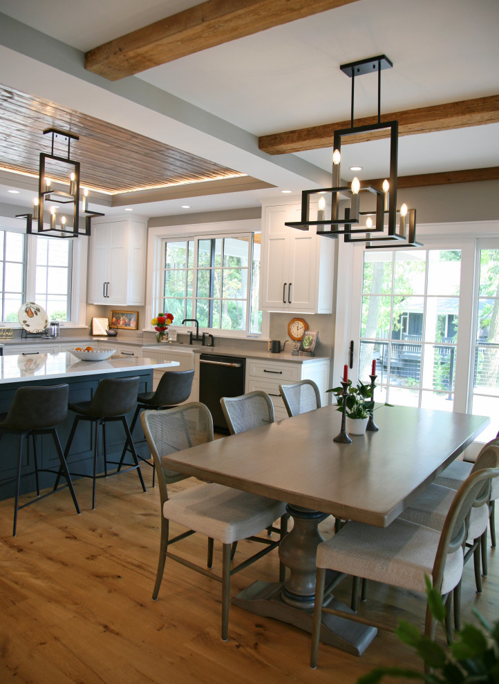 Esempio di una sala da pranzo aperta verso la cucina costiera di medie dimensioni con pareti grigie, pavimento in legno massello medio, pavimento marrone e travi a vista