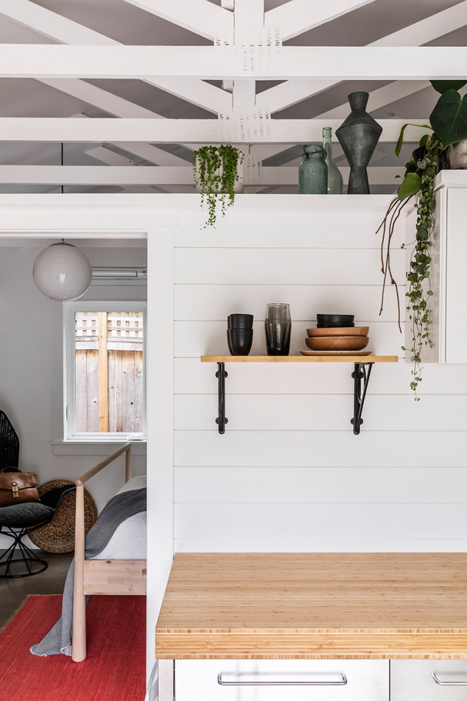 This is an example of a small beach style single-wall eat-in kitchen in Portland with a single-bowl sink, wood benchtops, white splashback, timber splashback, stainless steel appliances, concrete floors and grey floor.