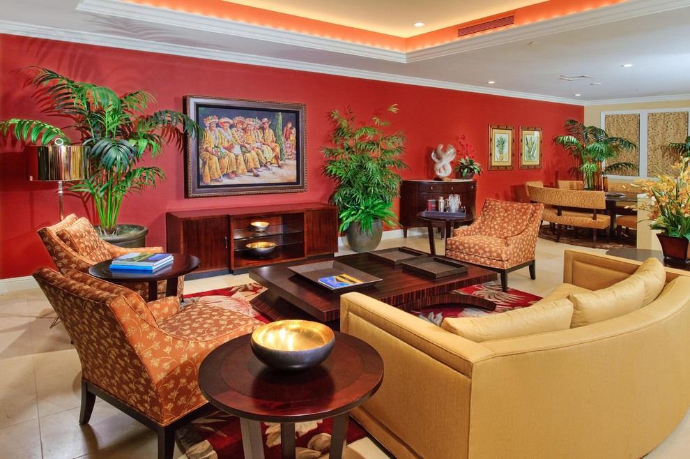 Tropical open concept living room in Hawaii with red walls, limestone floors and a concealed tv.
