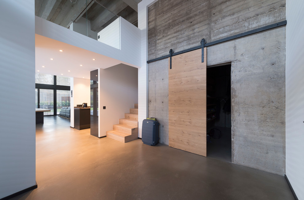 This is an example of a large industrial foyer in Other with white walls, concrete floors and grey floor.