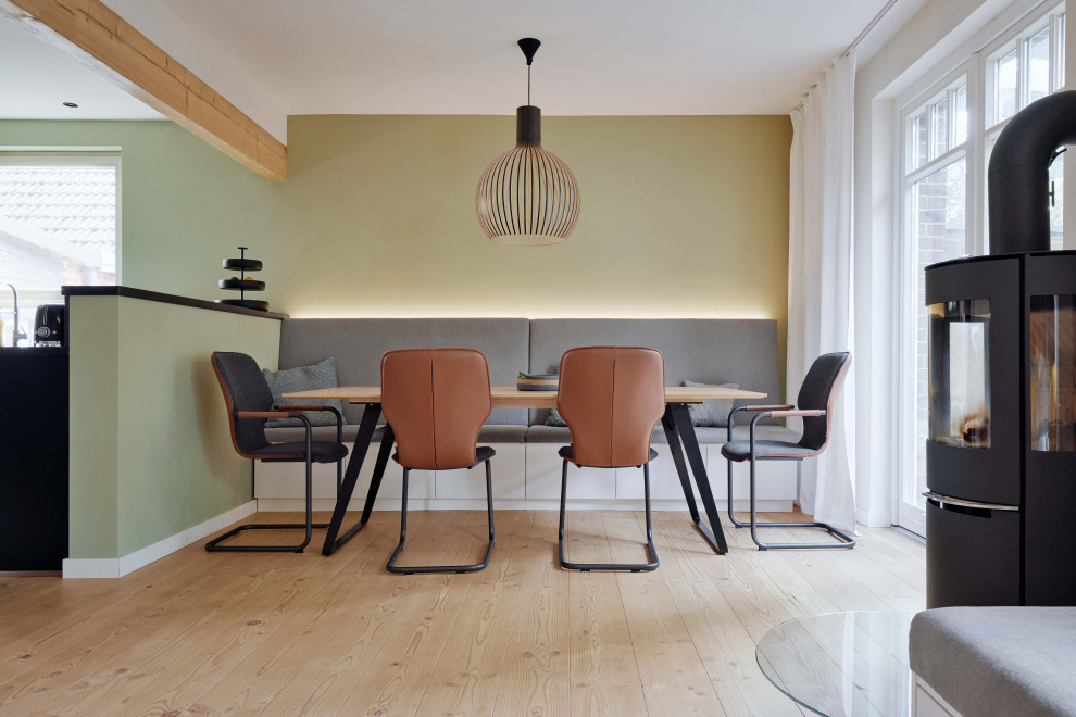 Foto di una sala da pranzo scandinava con pareti gialle, parquet chiaro, stufa a legna e travi a vista