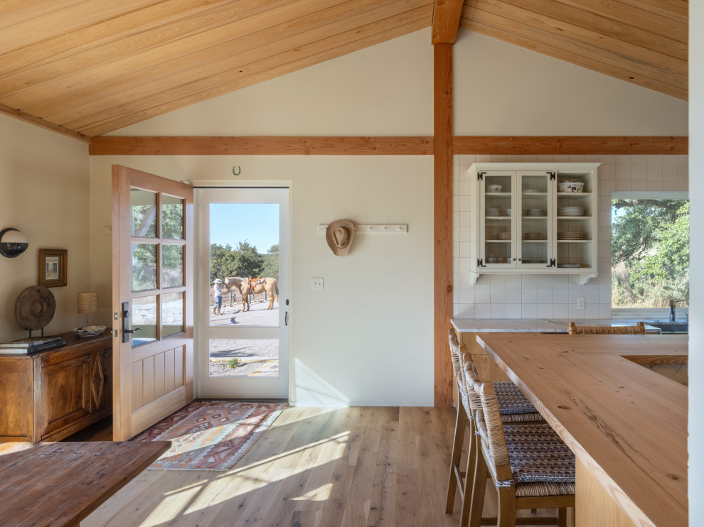 Example of a mid-sized cottage light wood floor and vaulted ceiling front door design in Austin with beige walls and a medium wood front door