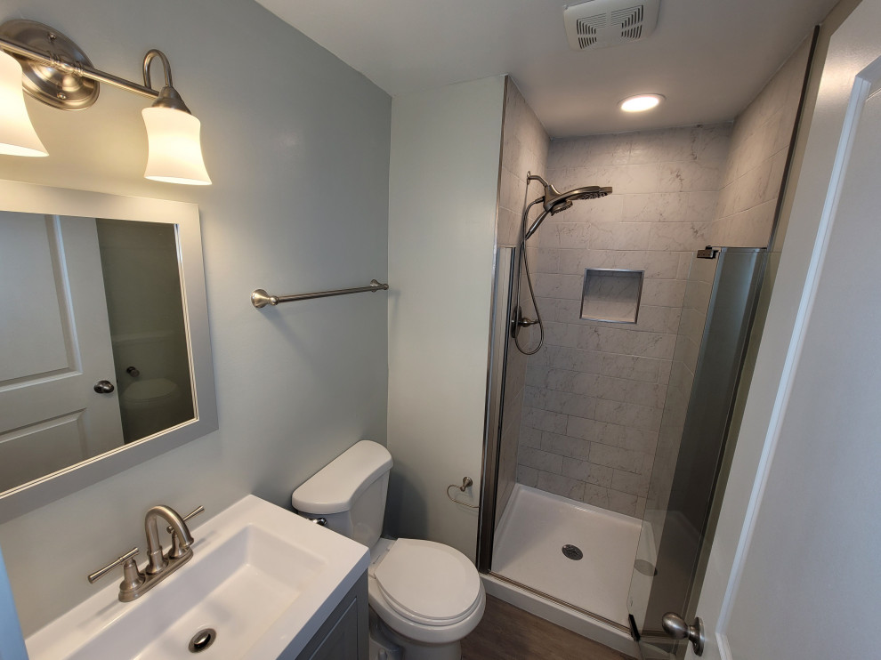 Small contemporary kids bathroom in DC Metro with shaker cabinets, grey cabinets, an alcove shower, a two-piece toilet, multi-coloured tile, ceramic tile, grey walls, vinyl floors, an integrated sink, marble benchtops, brown floor, a hinged shower door, white benchtops, a single vanity and a freestanding vanity.
