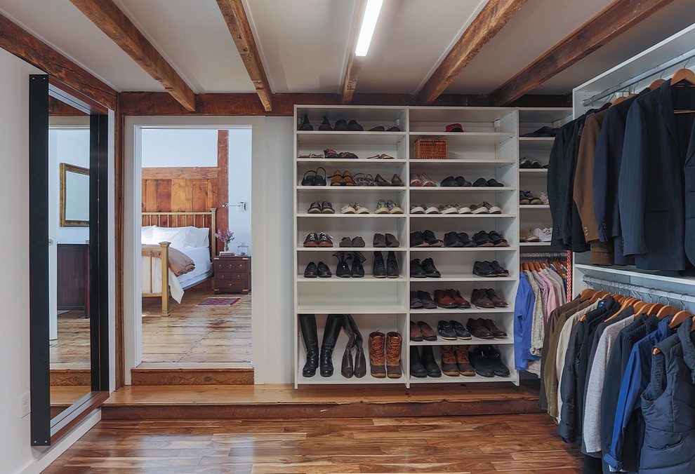 Inspiration for a large country gender-neutral walk-in wardrobe in Boston with open cabinets, white cabinets, medium hardwood floors and brown floor.