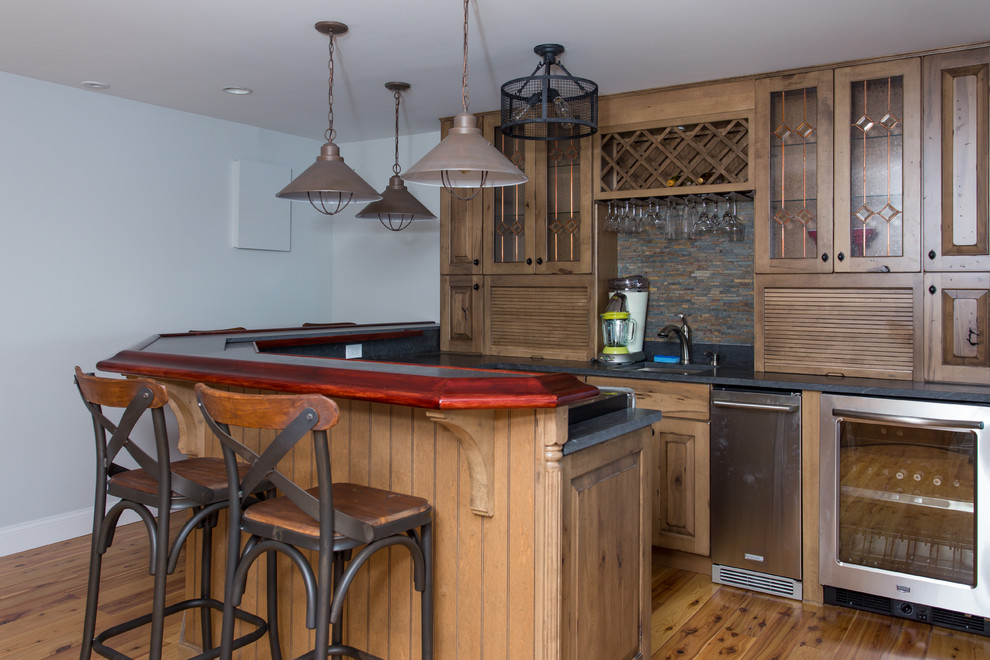 Inspiration for a large traditional single-wall seated home bar in Boston with an undermount sink, raised-panel cabinets, dark wood cabinets, soapstone benchtops, multi-coloured splashback, matchstick tile splashback and medium hardwood floors.