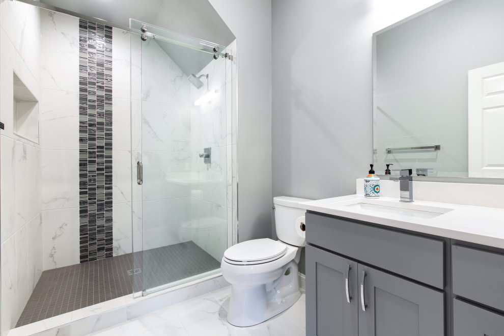 На фото: маленькая ванная комната в стиле модернизм с фасадами в стиле шейкер, серыми фасадами, открытым душем, унитазом-моноблоком, серой плиткой, керамогранитной плиткой, серыми стенами, полом из керамогранита, душевой кабиной, накладной раковиной, столешницей из искусственного кварца, разноцветным полом, душем с раздвижными дверями, белой столешницей, нишей, тумбой под одну раковину и напольной тумбой для на участке и в саду с