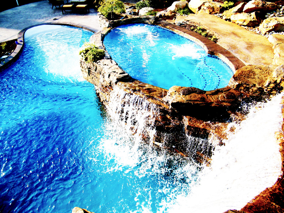 Exemple d'une grande piscine naturelle et arrière tendance avec du béton estampé et un bain bouillonnant.