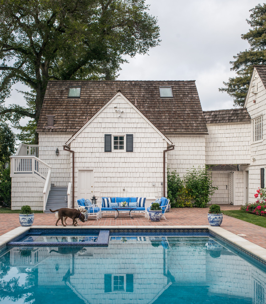This is an example of a large traditional backyard rectangular lap pool in San Francisco with a hot tub and brick pavers.