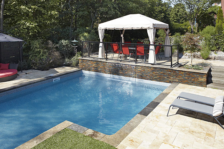 Large contemporary backyard l-shaped natural pool in Toronto with a water feature and natural stone pavers.