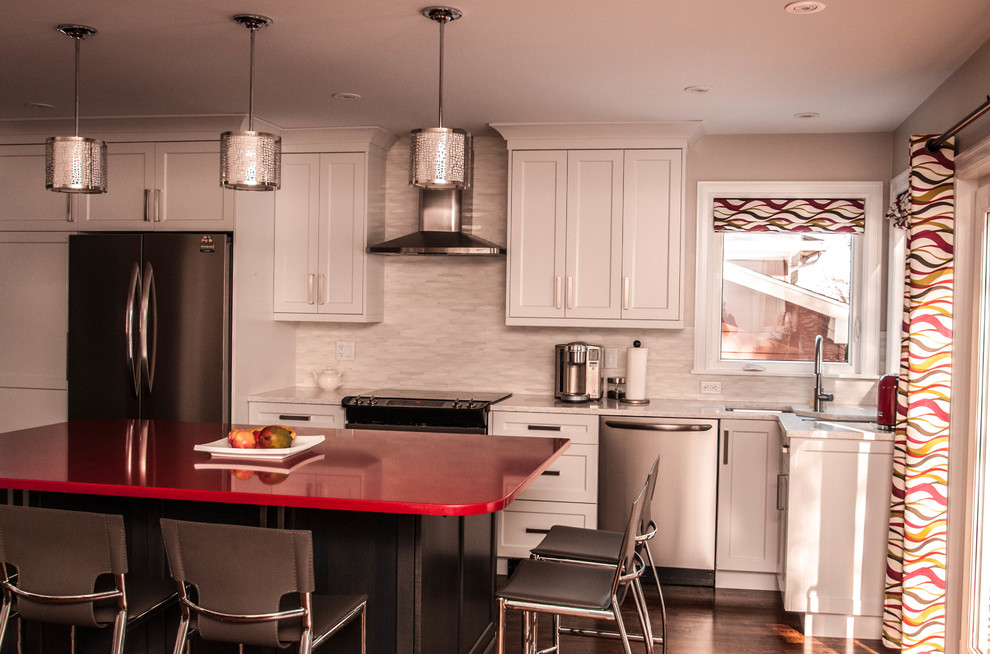Mid-sized transitional l-shaped medium tone wood floor eat-in kitchen photo with an undermount sink, shaker cabinets, white cabinets, quartz countertops, gray backsplash, stone tile backsplash, stainless steel appliances and an island
