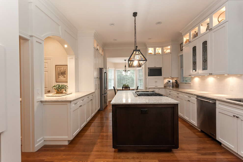 Design ideas for an expansive transitional u-shaped eat-in kitchen in Charleston with with island, recessed-panel cabinets, white cabinets, recycled glass benchtops, an undermount sink, white splashback, ceramic splashback, stainless steel appliances, medium hardwood floors and beige floor.