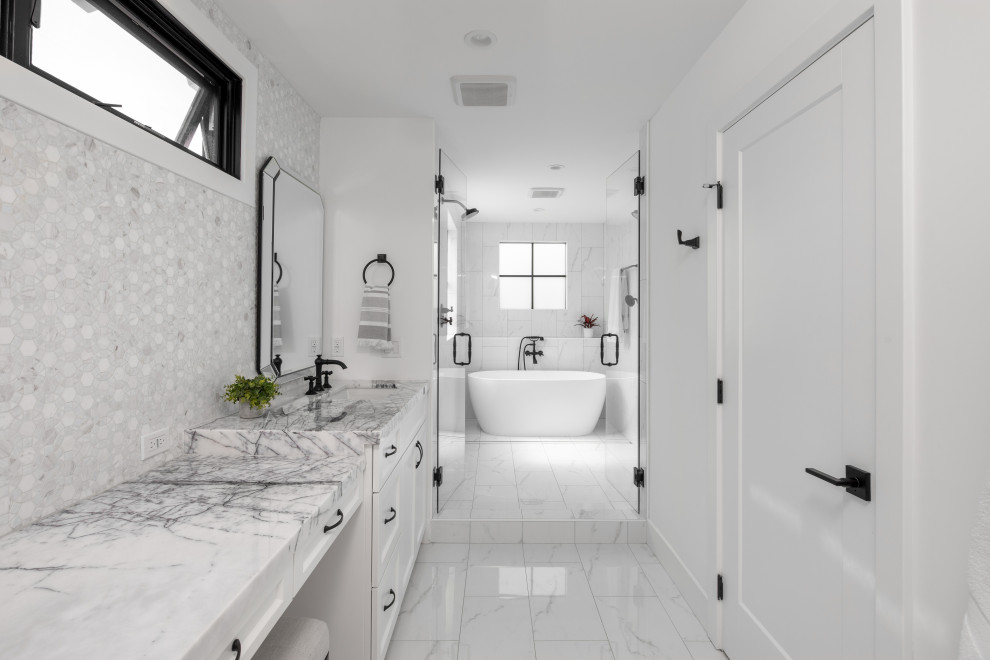 Пример оригинального дизайна: большая главная ванная комната в стиле кантри с фасадами в стиле шейкер, белыми фасадами, отдельно стоящей ванной, душевой комнатой, унитазом-моноблоком, бежевой плиткой, мраморной плиткой, белыми стенами, полом из керамической плитки, врезной раковиной, столешницей из кварцита, белым полом, душем с распашными дверями, белой столешницей, нишей, тумбой под две раковины и встроенной тумбой