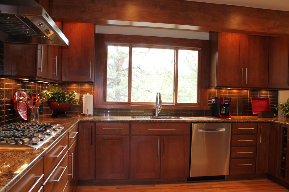 Inspiration for a large transitional u-shaped light wood floor eat-in kitchen remodel in Denver with an undermount sink, flat-panel cabinets, dark wood cabinets, granite countertops, brown backsplash, glass tile backsplash, stainless steel appliances and a peninsula