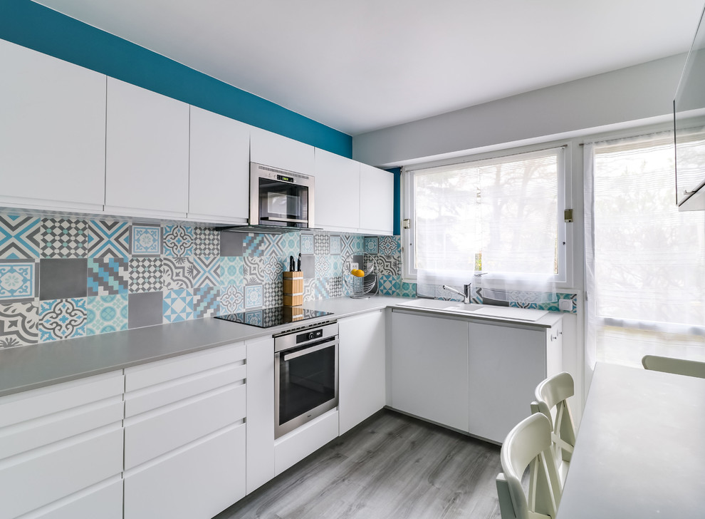 Mid-sized contemporary l-shaped separate kitchen in Paris with a double-bowl sink, beaded inset cabinets, white cabinets, quartzite benchtops, blue splashback, cement tile splashback, stainless steel appliances, painted wood floors, no island, grey floor and grey benchtop.