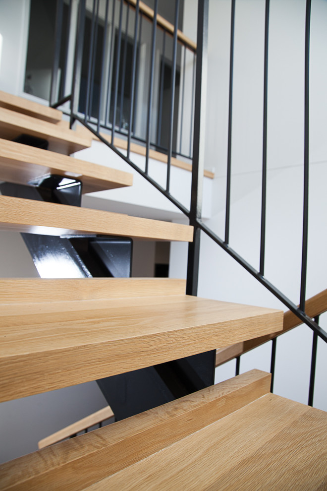 Mid-sized contemporary wood u-shaped staircase in Auckland with open risers.
