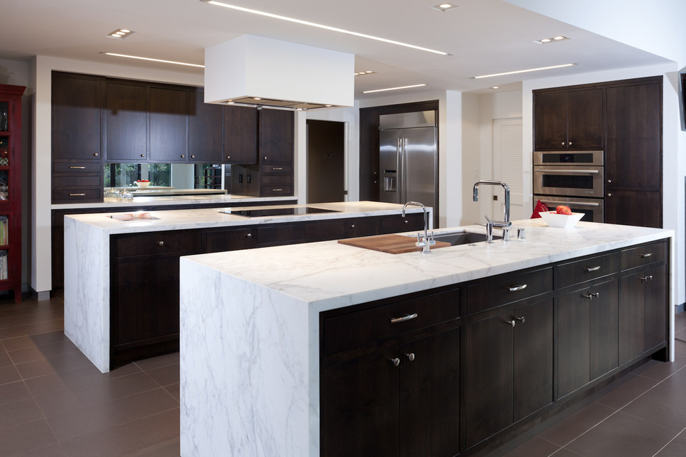 Photo of an expansive contemporary galley eat-in kitchen in Sacramento with flat-panel cabinets, stainless steel appliances, dark wood cabinets, marble benchtops, mirror splashback, multiple islands and an undermount sink.