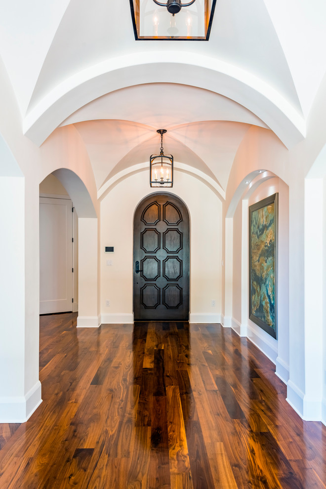 Inspiration for a large mediterranean foyer in Tampa with white walls, medium hardwood floors, a single front door, a dark wood front door and brown floor.
