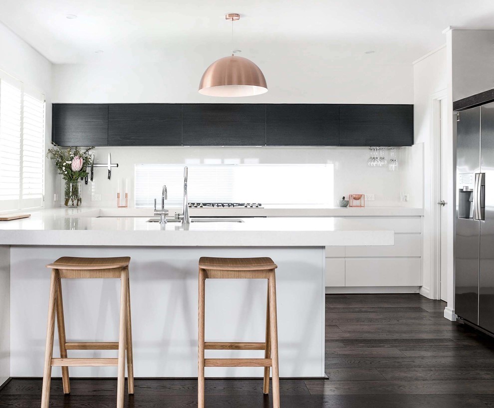 Mid-sized contemporary u-shaped eat-in kitchen in Perth with flat-panel cabinets, black cabinets, quartz benchtops, white splashback, glass sheet splashback, black appliances and with island.