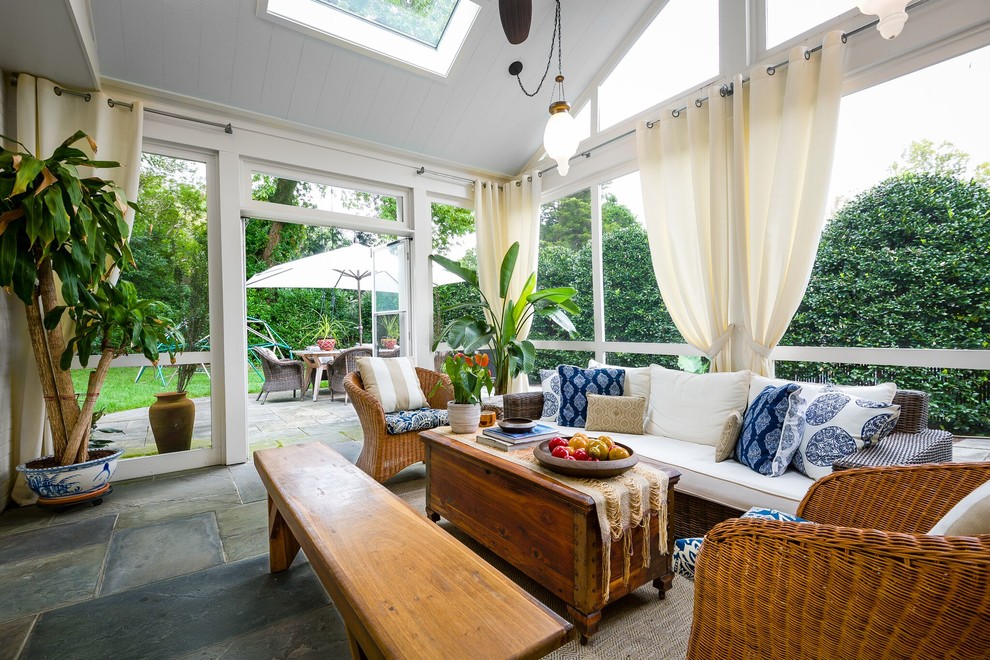 Photo of a tropical sunroom in DC Metro with no fireplace, a skylight and grey floor.