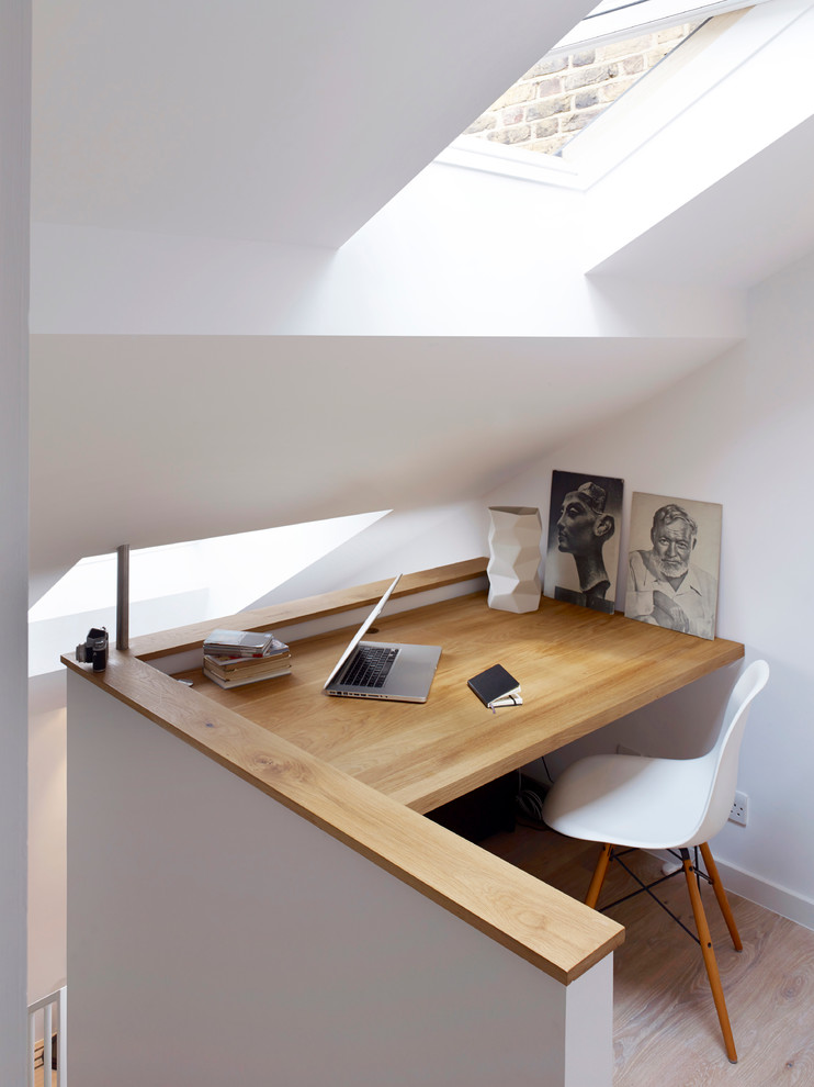 Small modern study room in London with white walls, light hardwood floors and a built-in desk.