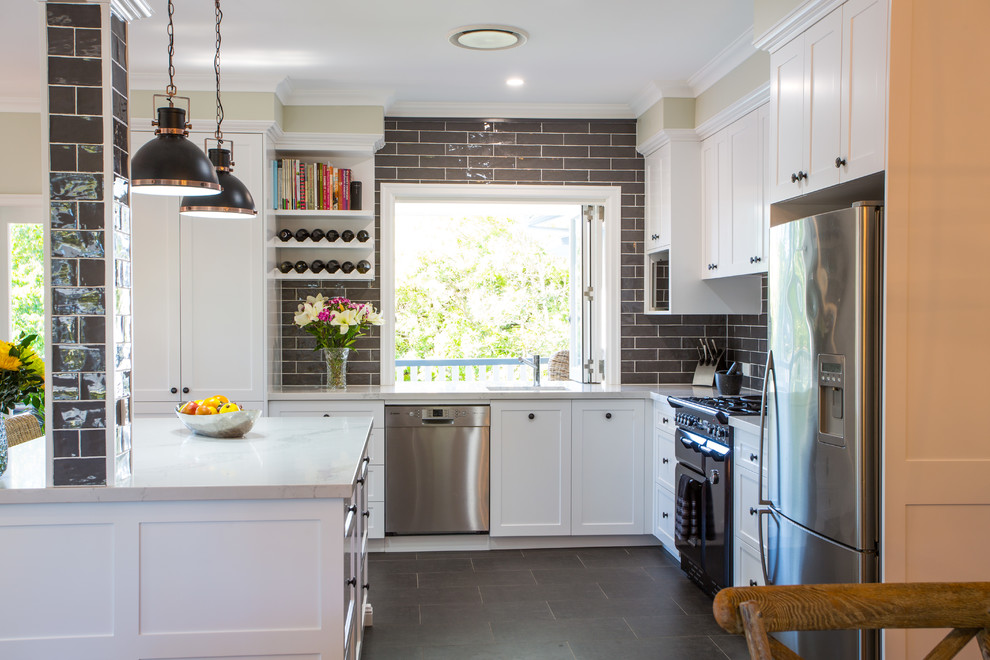Photo of a large traditional l-shaped open plan kitchen in Brisbane with an undermount sink, shaker cabinets, white cabinets, quartz benchtops, grey splashback, black appliances, ceramic floors, with island and grey floor.