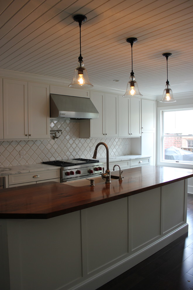 Example of a large transitional galley dark wood floor eat-in kitchen design in Baltimore with a farmhouse sink, shaker cabinets, white cabinets, wood countertops, white backsplash, ceramic backsplash, stainless steel appliances and an island