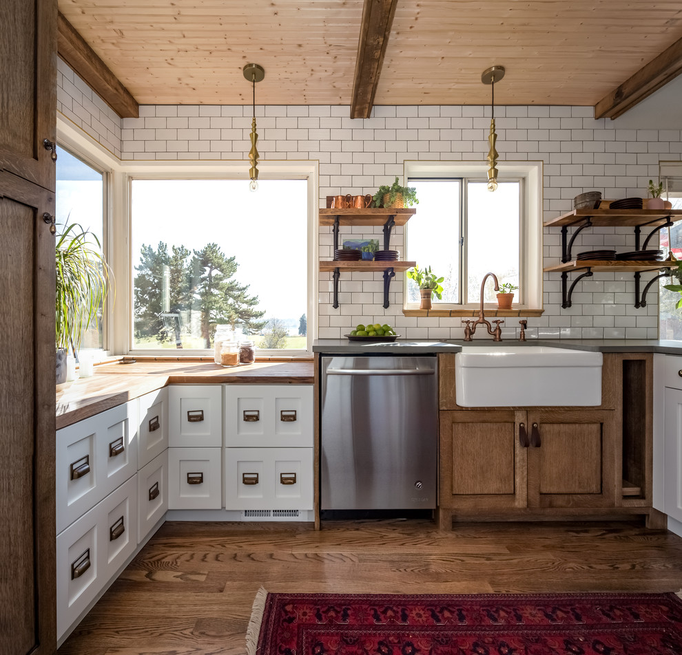 Small country u-shaped kitchen in Denver with a farmhouse sink, shaker cabinets, wood benchtops, white splashback, ceramic splashback, stainless steel appliances, a peninsula, white cabinets, medium hardwood floors, brown floor, brown benchtop and timber.