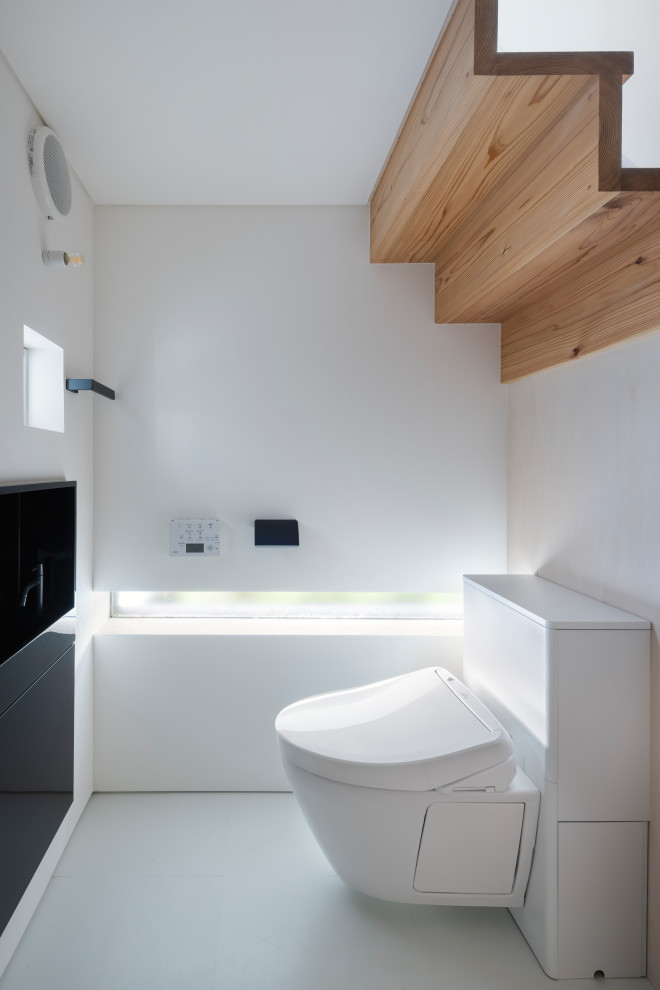 Cette image montre un WC suspendu minimaliste avec un mur blanc, un sol en linoléum, un sol blanc, un plafond en papier peint et du papier peint.