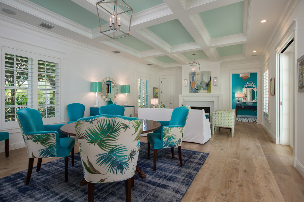 Photo of a large tropical separate dining room in Miami with white walls, light hardwood floors, a standard fireplace, a stone fireplace surround and beige floor.