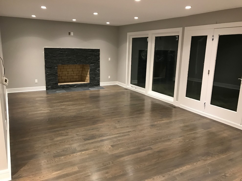 Design ideas for a large transitional formal enclosed living room in Chicago with grey walls, medium hardwood floors, a standard fireplace, a stone fireplace surround, no tv and brown floor.