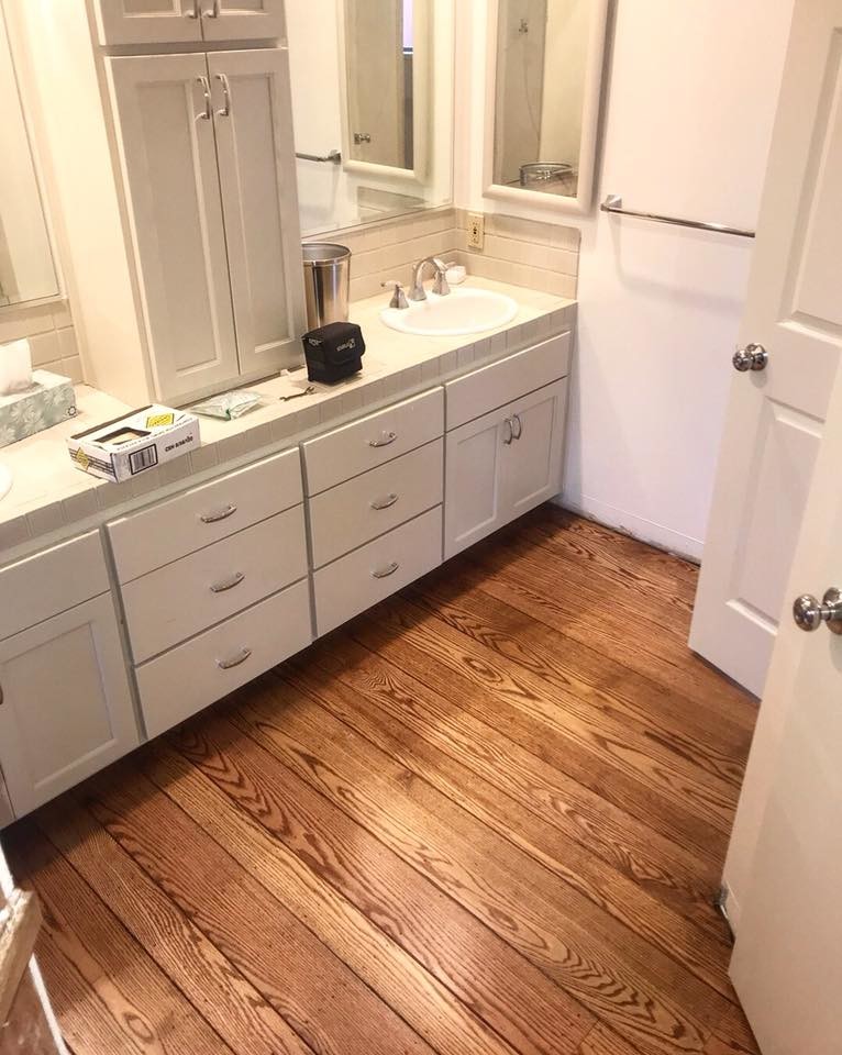 This is an example of a mid-sized country master bathroom in San Francisco with open cabinets, white cabinets, white walls, dark hardwood floors, a drop-in sink, tile benchtops and brown floor.
